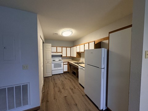 A kitchen with white appliances and wooden floors.