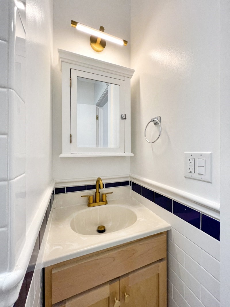 a bathroom with a sink and a mirror and a refrigerator