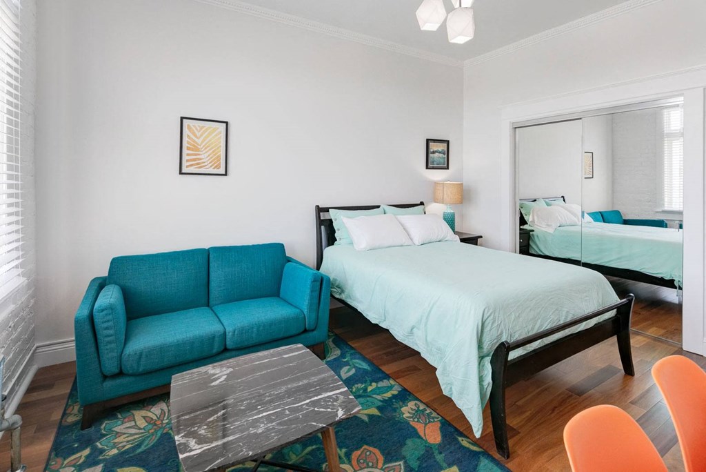 a bedroom with a bed and a couch and a mirror