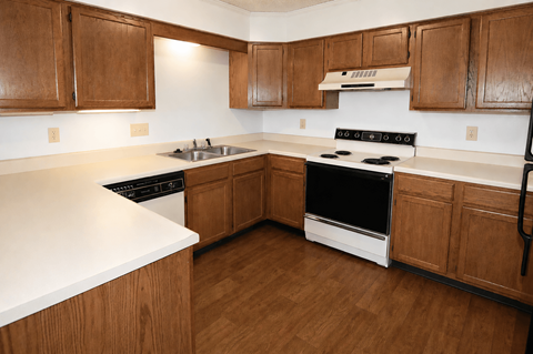A kitchen with wooden cabinets and a white counter top.