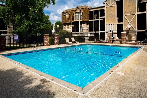A swimming pool in front of a building with a fence around it.