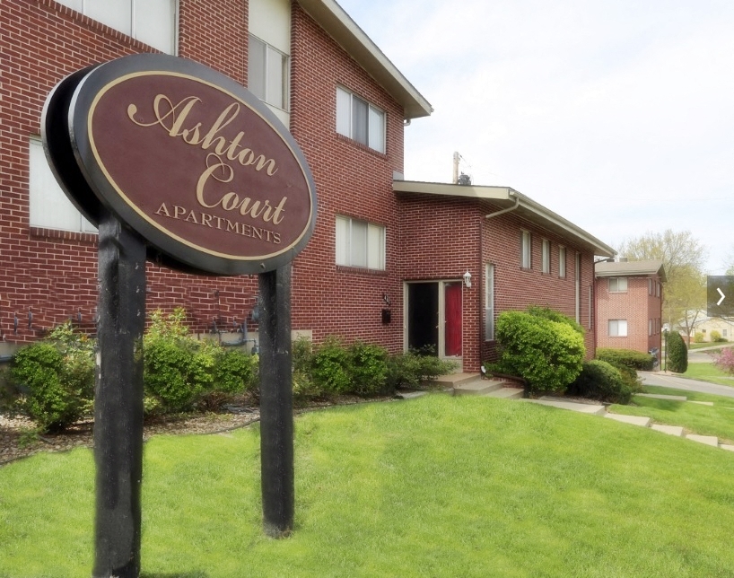 a red brick building with a sign in front of a lawn