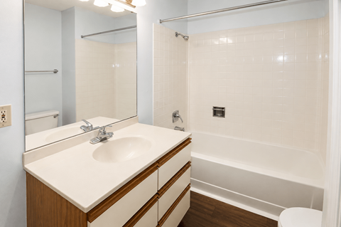 A white sink with a wooden counter top and a white toilet in a bathroom.