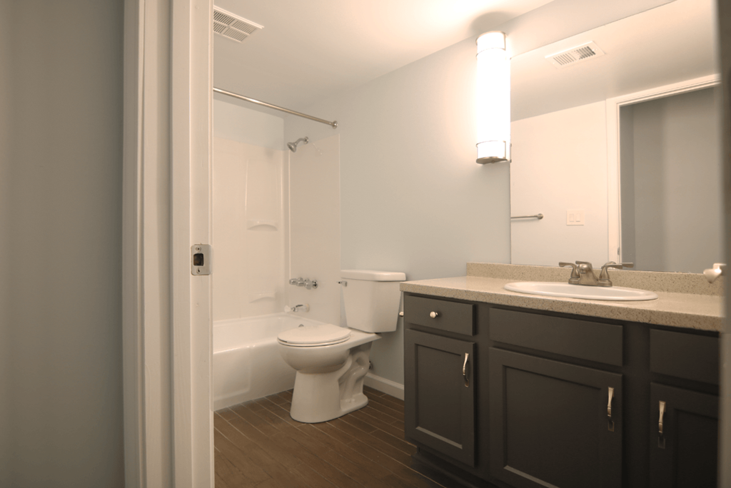 A white toilet sits in a bathroom with a sink and mirror.