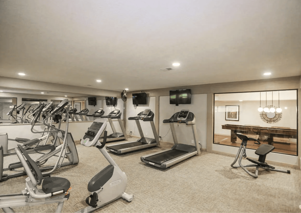 A spacious gym with treadmills, exercise bikes, and a television. at The Ridge Overland Park, Overland Park, KS, 66212