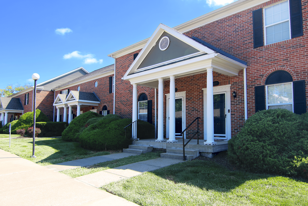 A red brick house with a white front porch.
