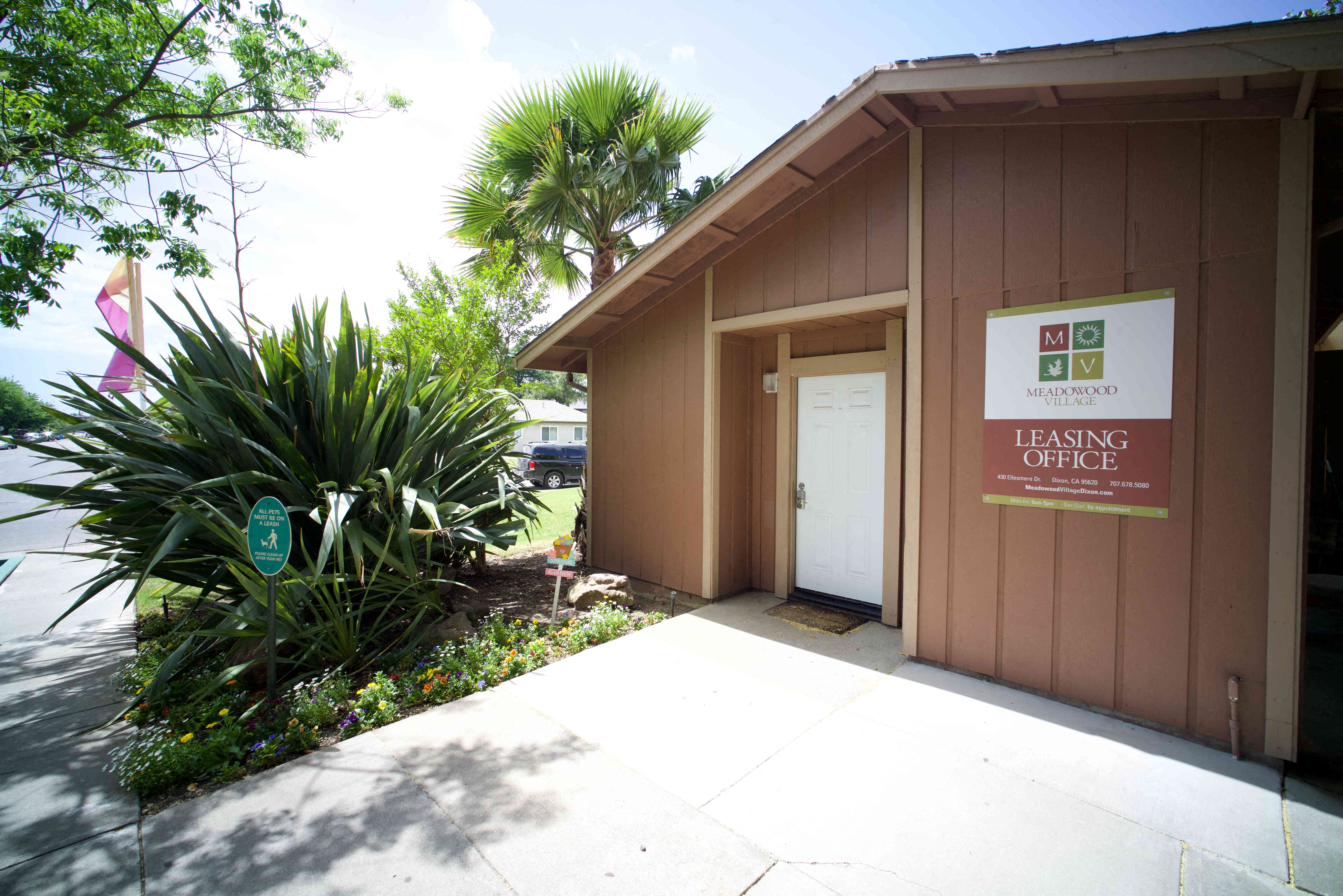 the front entrance of the housing office with a sidewalk and palm trees