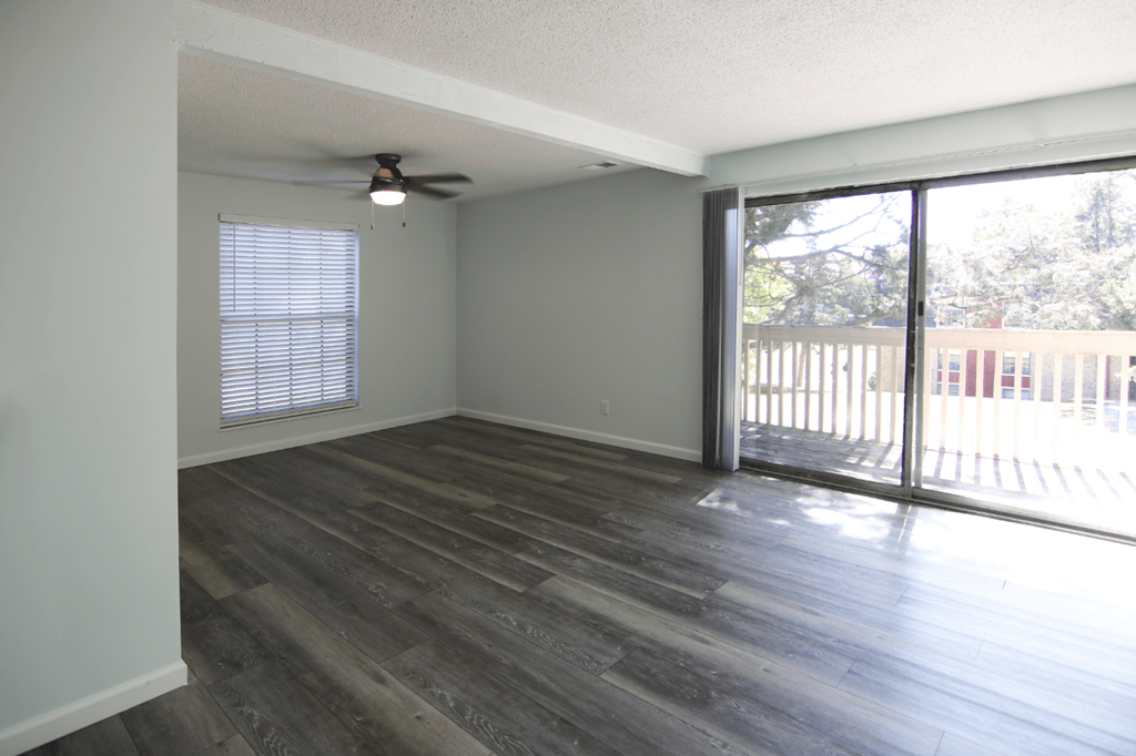 A room with a ceiling fan and sliding glass doors.