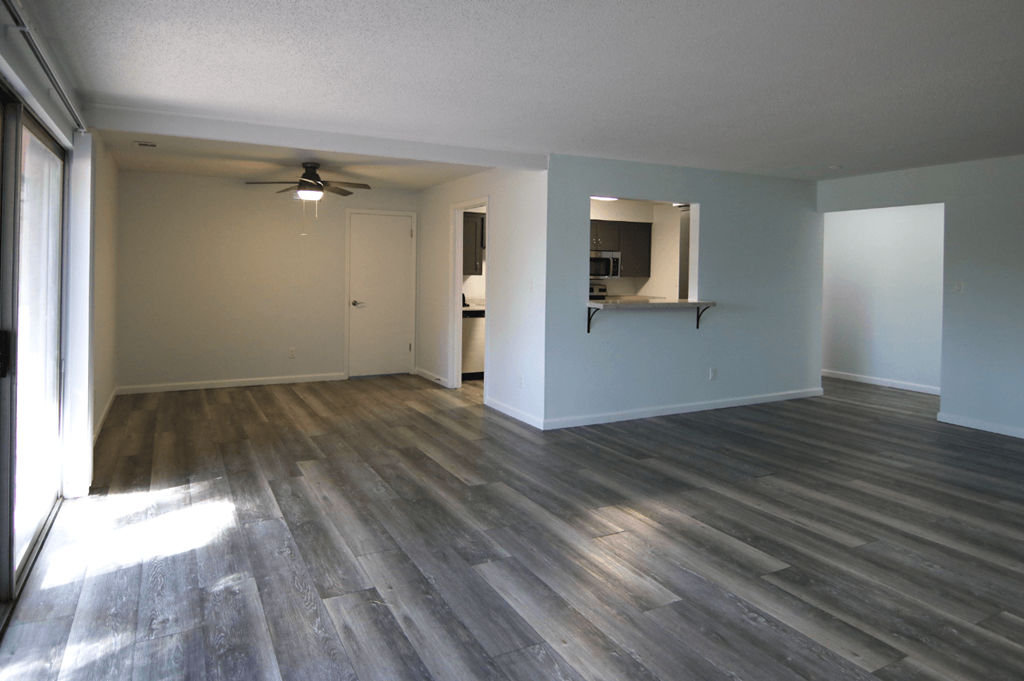 A room with a ceiling fan and wood flooring.