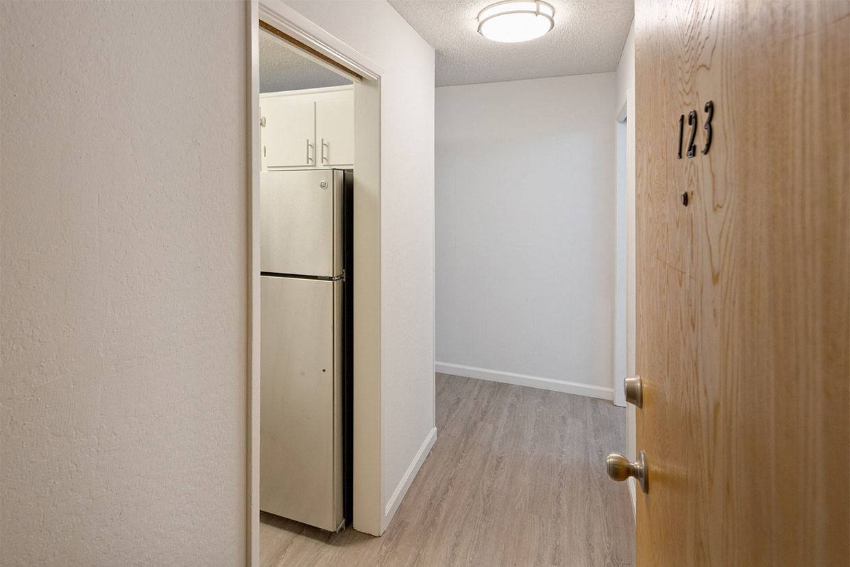 an empty room with a refrigerator and a door