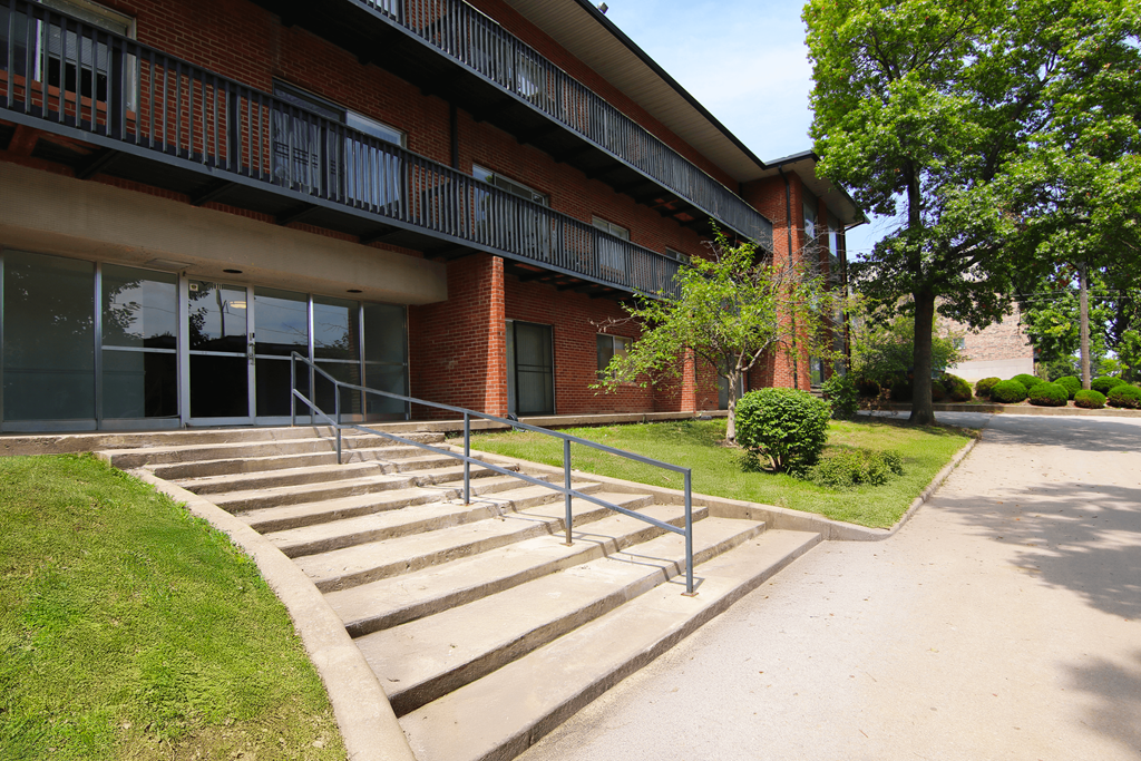 A red brick building with a metal railing on the balcony.