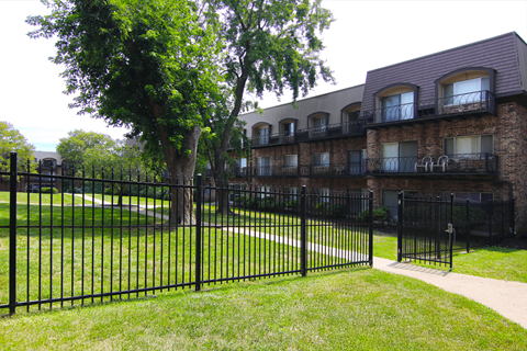 A black iron fence surrounds a green lawn.