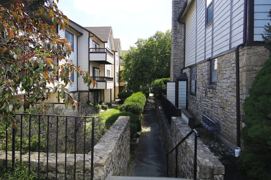 A narrow alley with a metal fence on the left and a stone wall on the right.