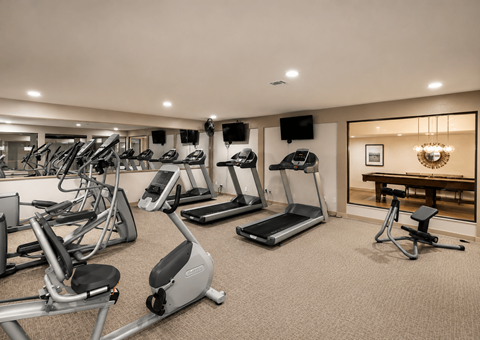 A well-lit gym with a variety of exercise equipment.