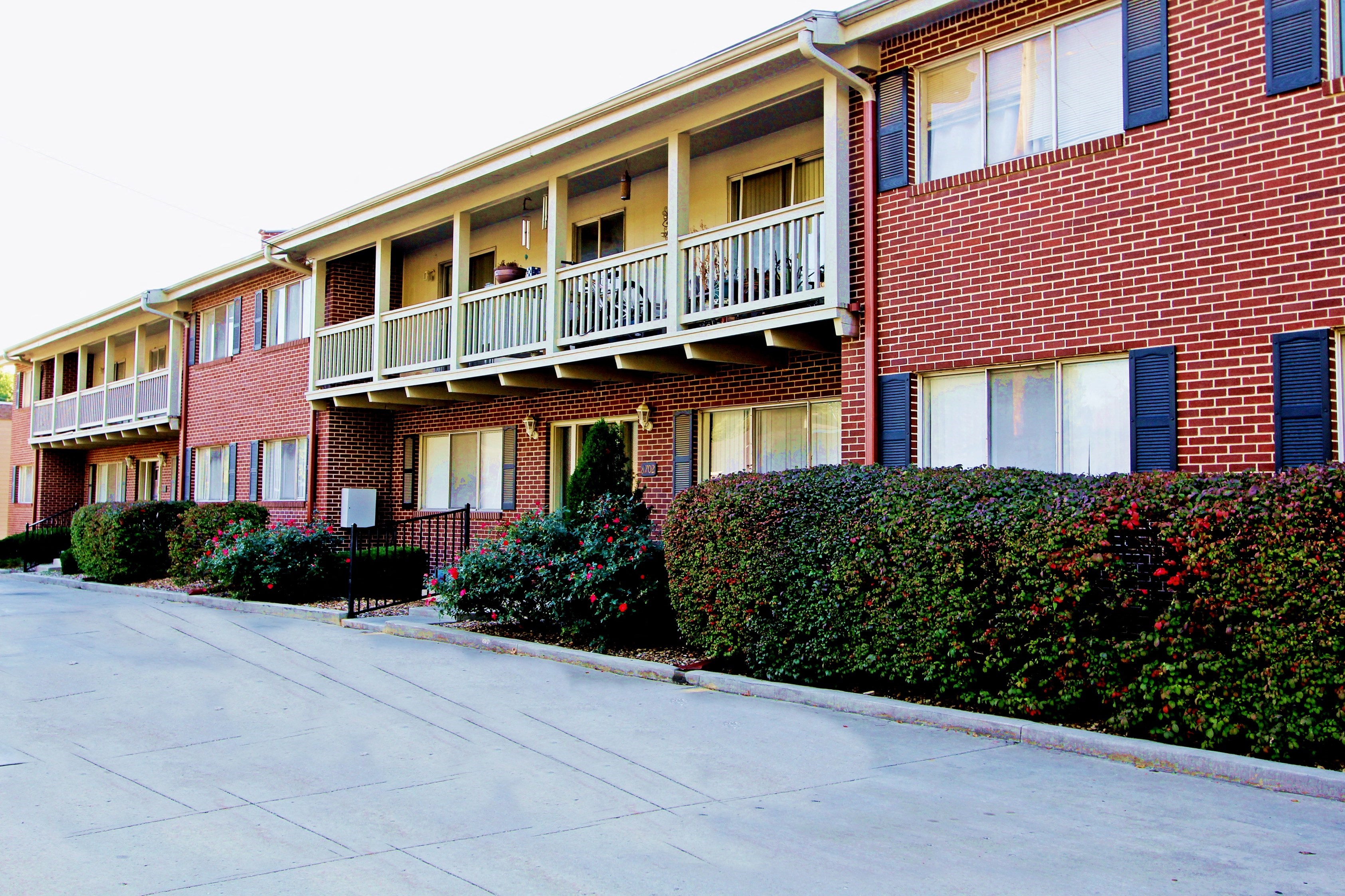 a red brick apartment building with a balcony and a sidewalk