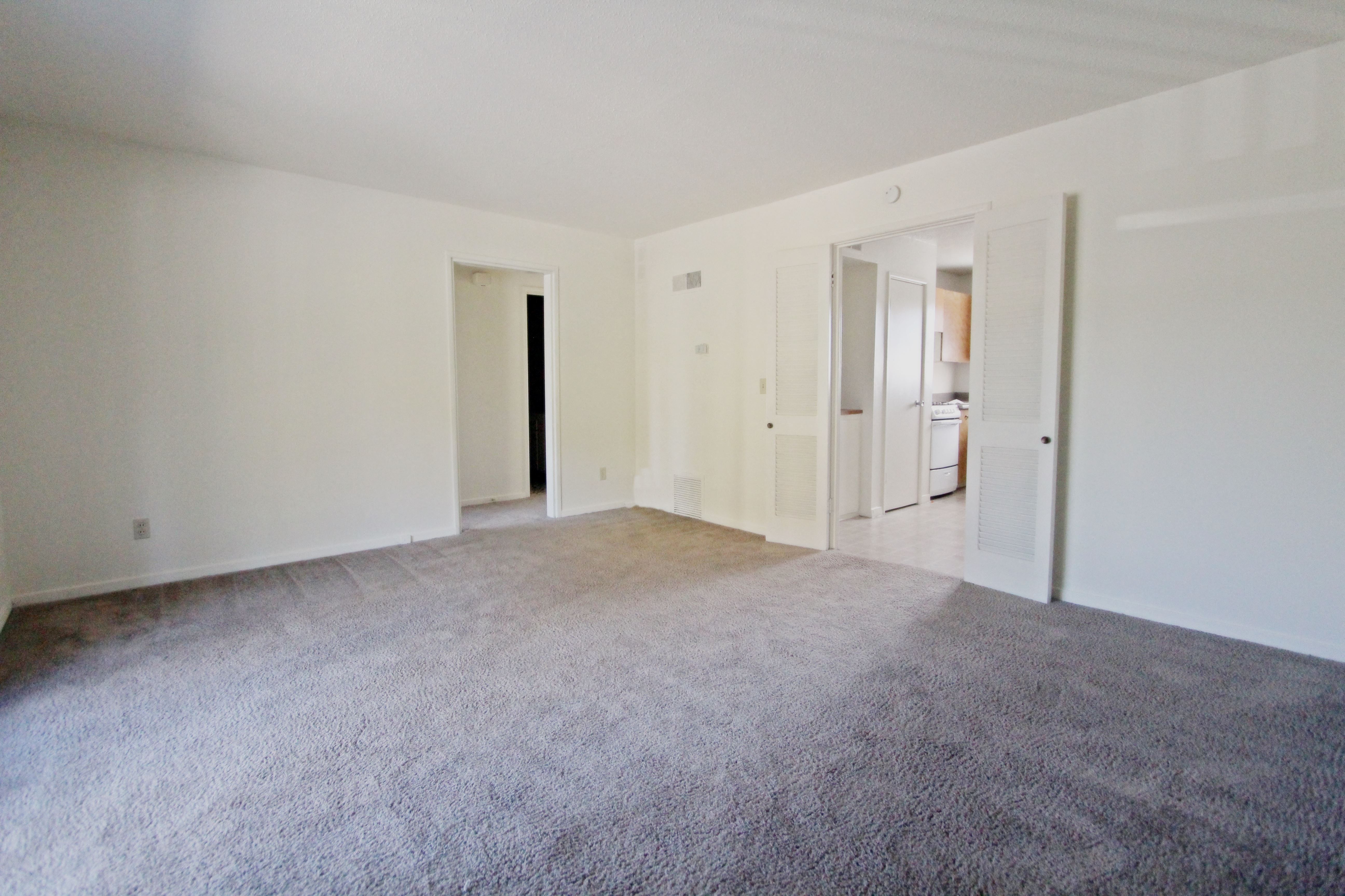 an empty living room with white walls and carpet