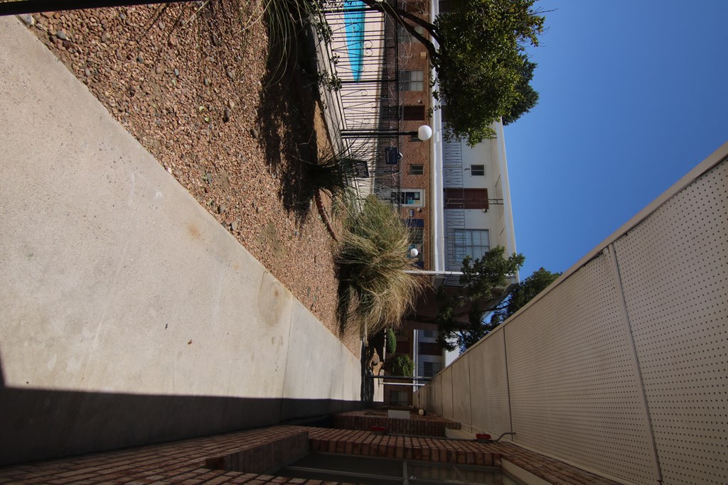 a courtyard with a water feature and a tall building in the background