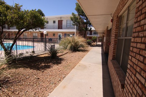 a walkway leading to a pool at the whispering winds apartments in pearland, tx