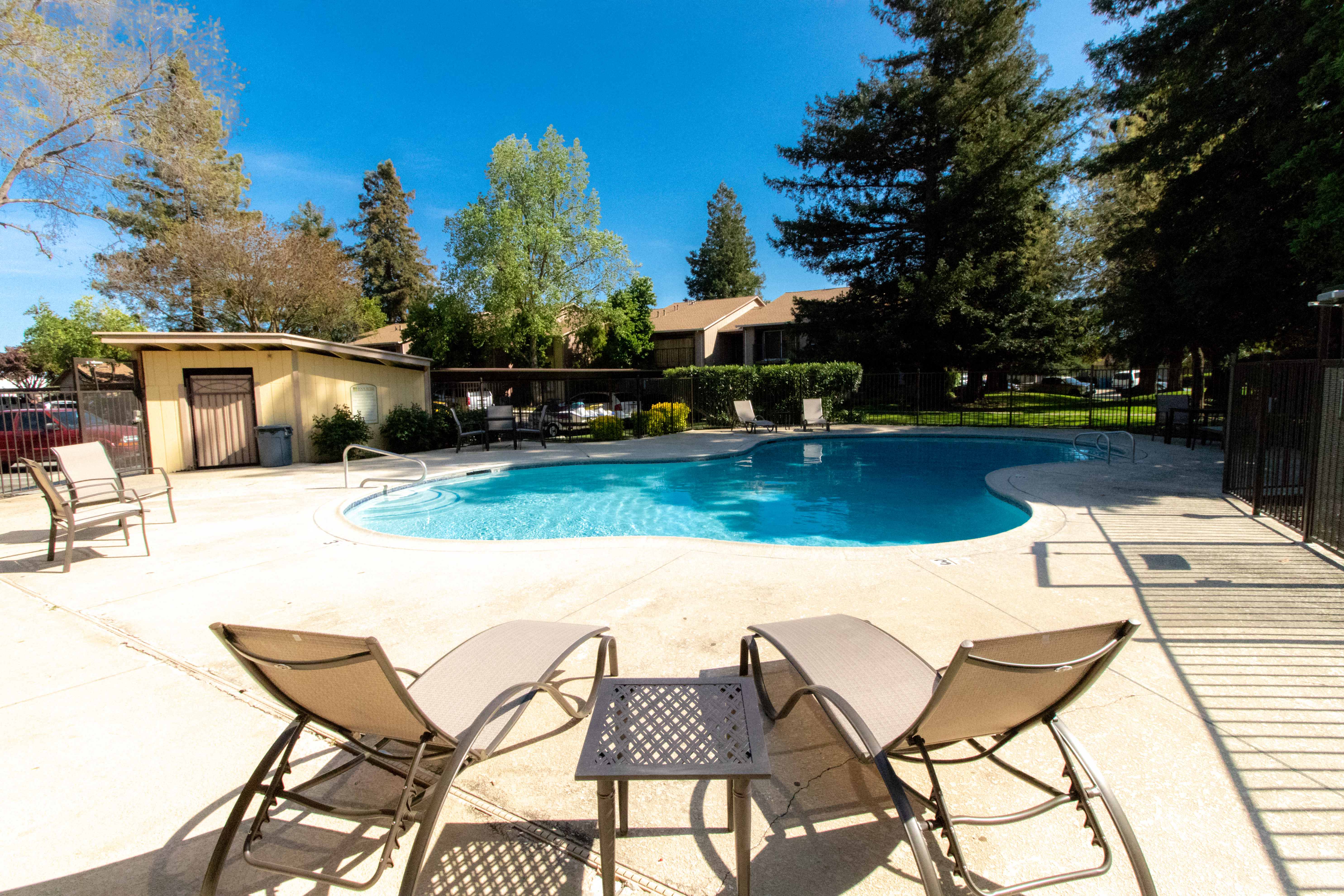 a swimming pool with chairs and tables around it