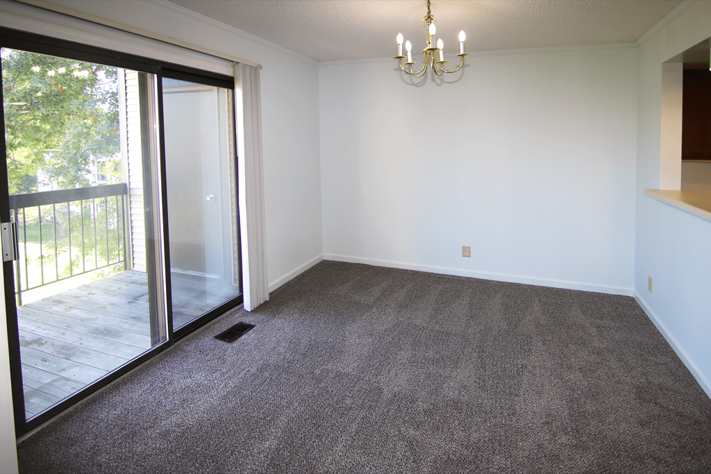 A room with a grey carpet and a chandelier.