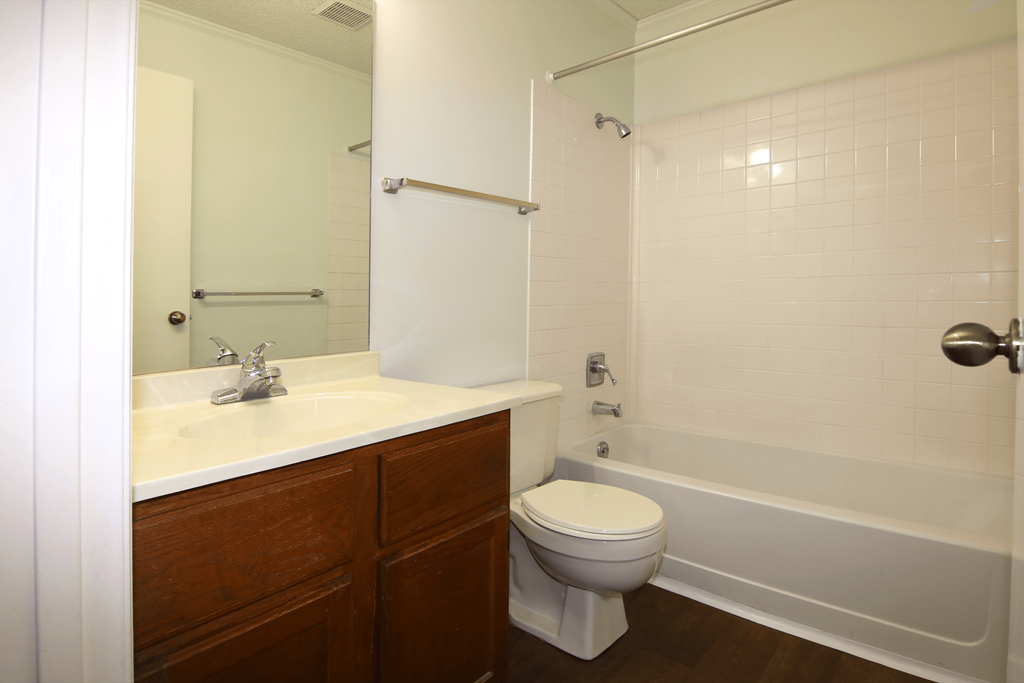 A white toilet sits next to a white bathtub in a bathroom.