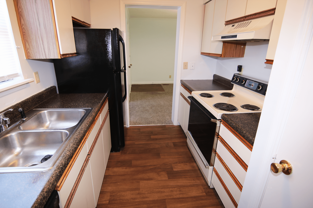 A kitchen with a black fridge and stove top oven.