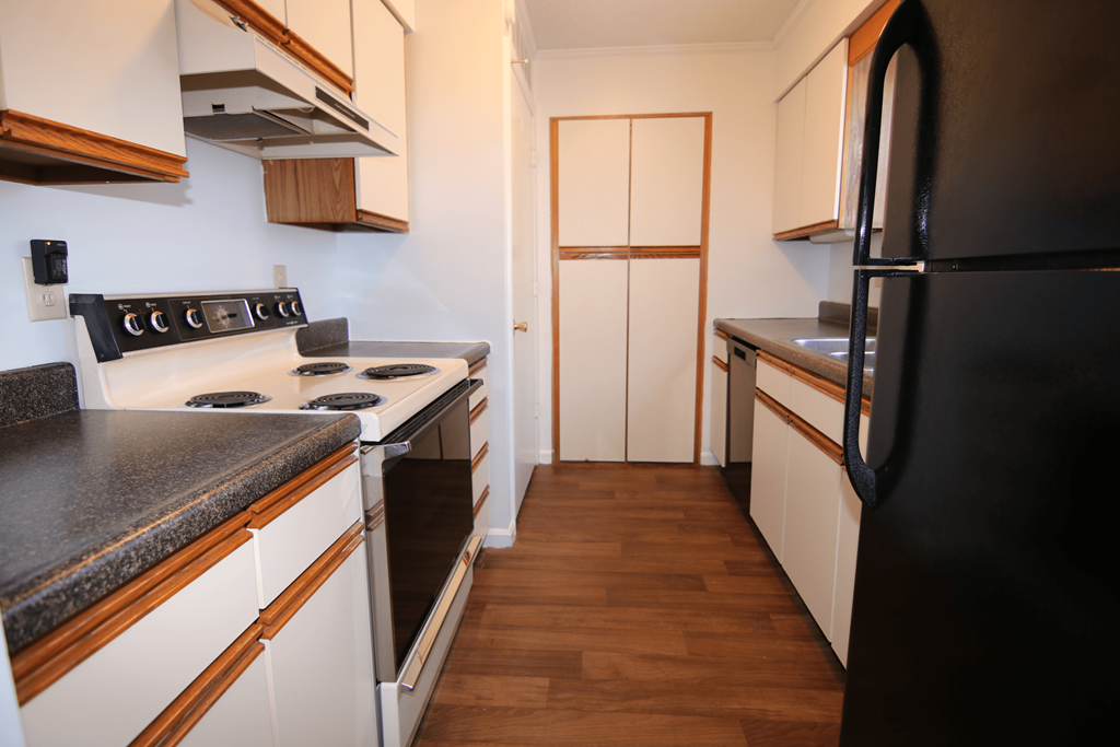 A kitchen with a black refrigerator and white cabinets.