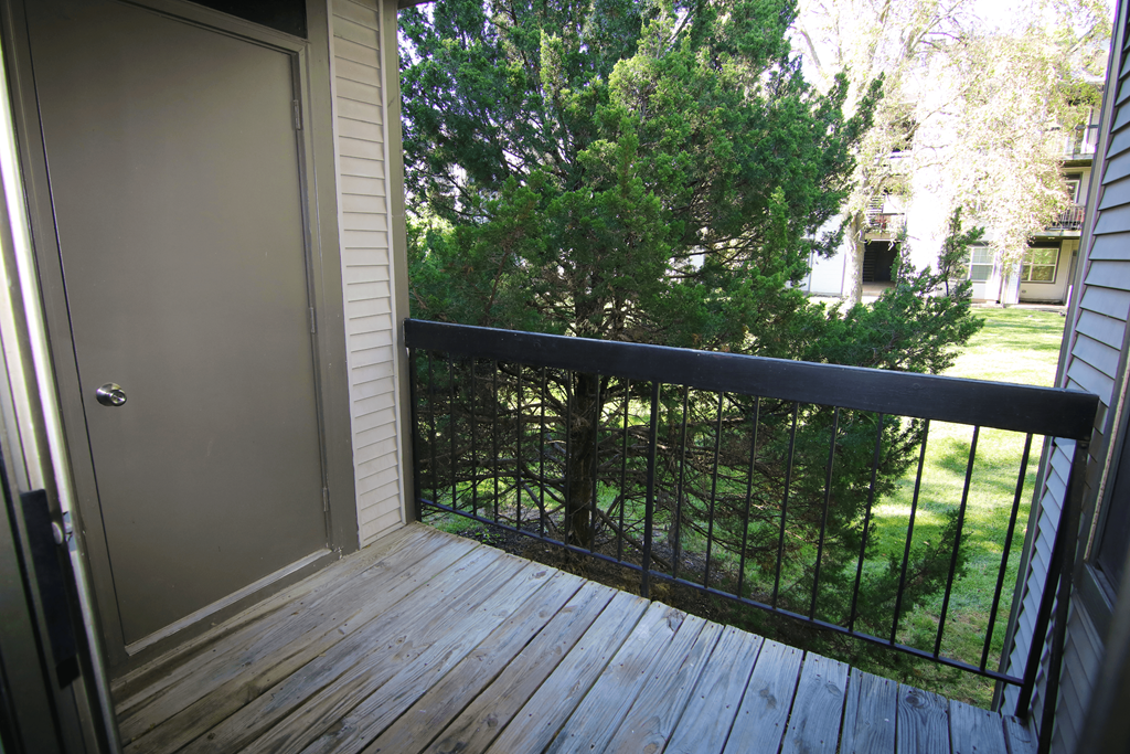 A balcony with a black railing and a brown door.