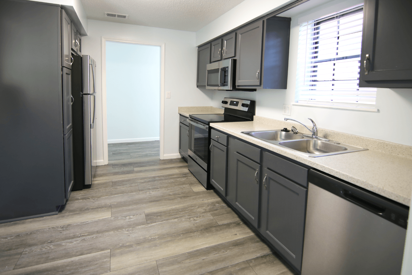 A kitchen with black cabinets and a stainless steel refrigerator.