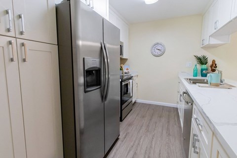A kitchen with a stainless steel refrigerator and wooden flooring.