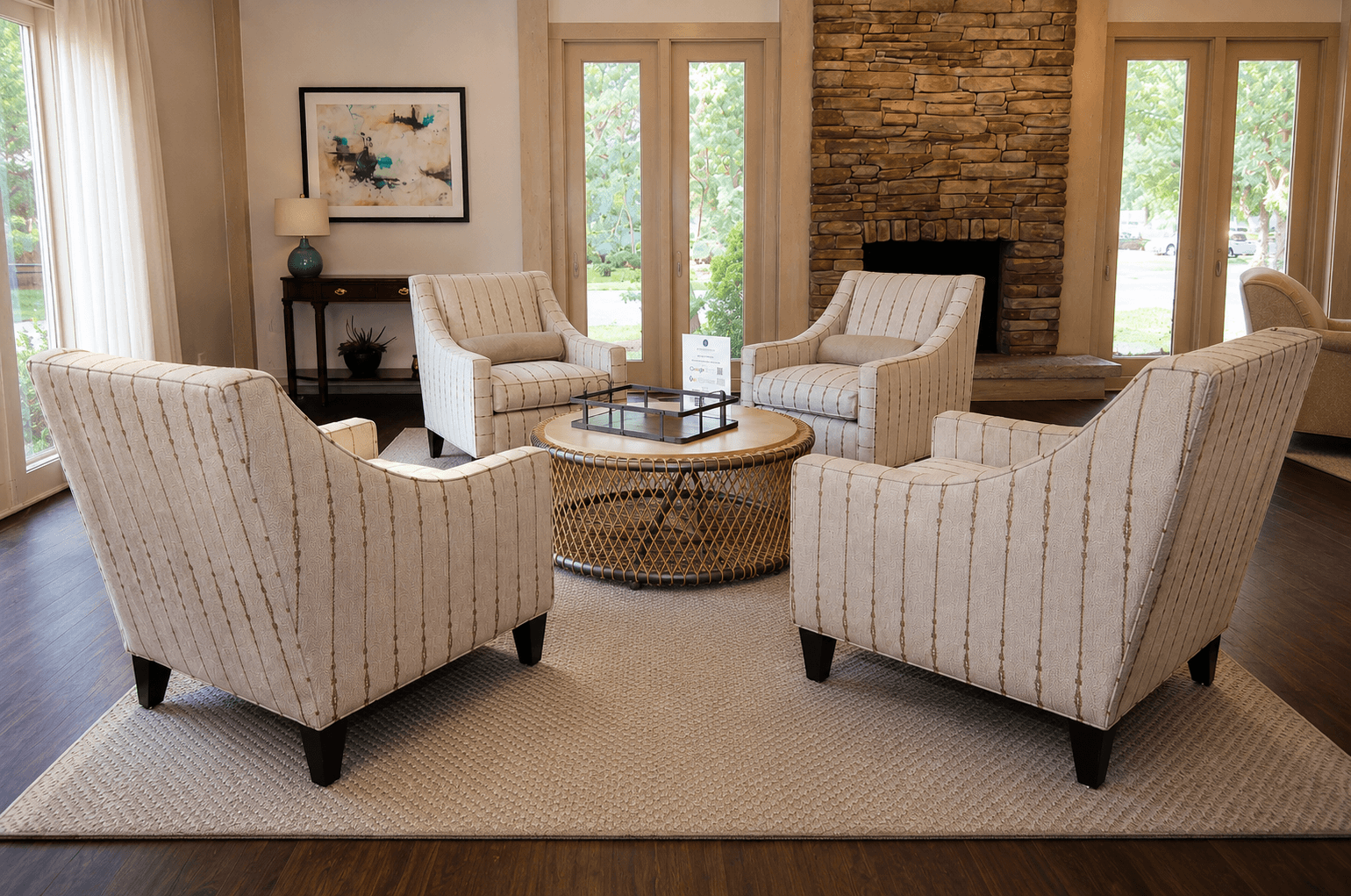 Four chairs are arranged around a coffee table in a room with a stone fireplace.