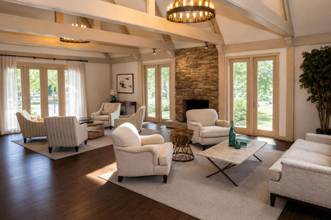 A living room with a stone fireplace and a chandelier.