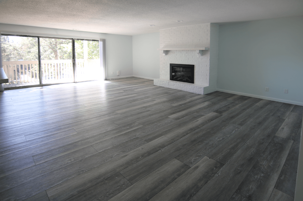 A large empty room with a fireplace and sliding glass doors.