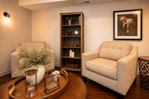 A living room with a sofa, a chair, a coffee table, and a bookshelf.