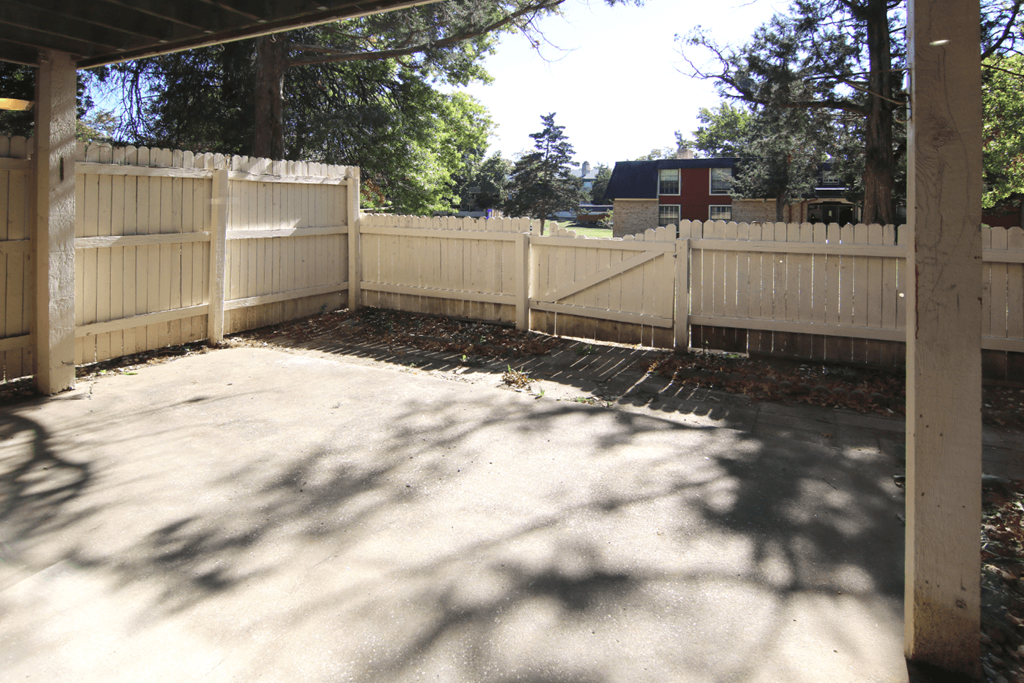 A white fence encloses a concrete patio.