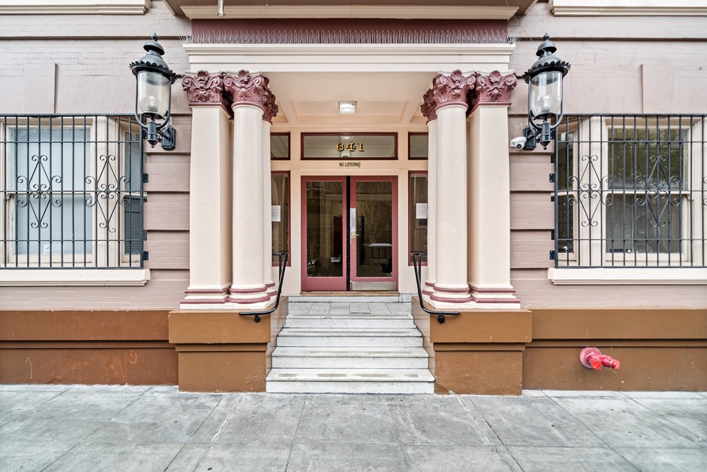 the front of a building with a red door and columns