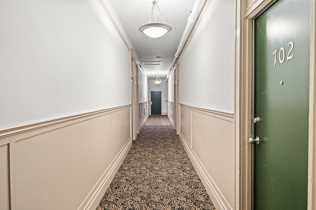 a hallway with a green door and a patterned carpet in a hotel room