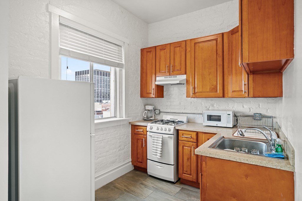 a kitchen with wooden cabinets and white appliances and a window