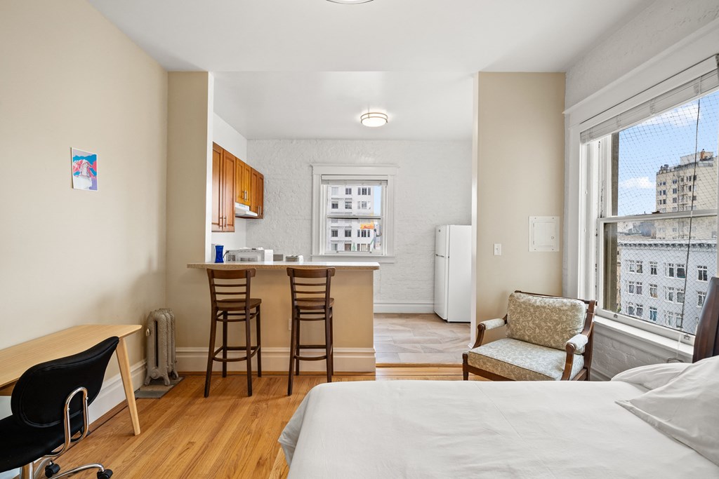 a bedroom with a bed and a kitchen with a bar and a large window