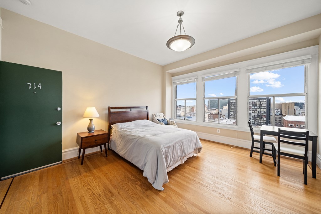 a bedroom with a bed and a large window and a desk with a chair