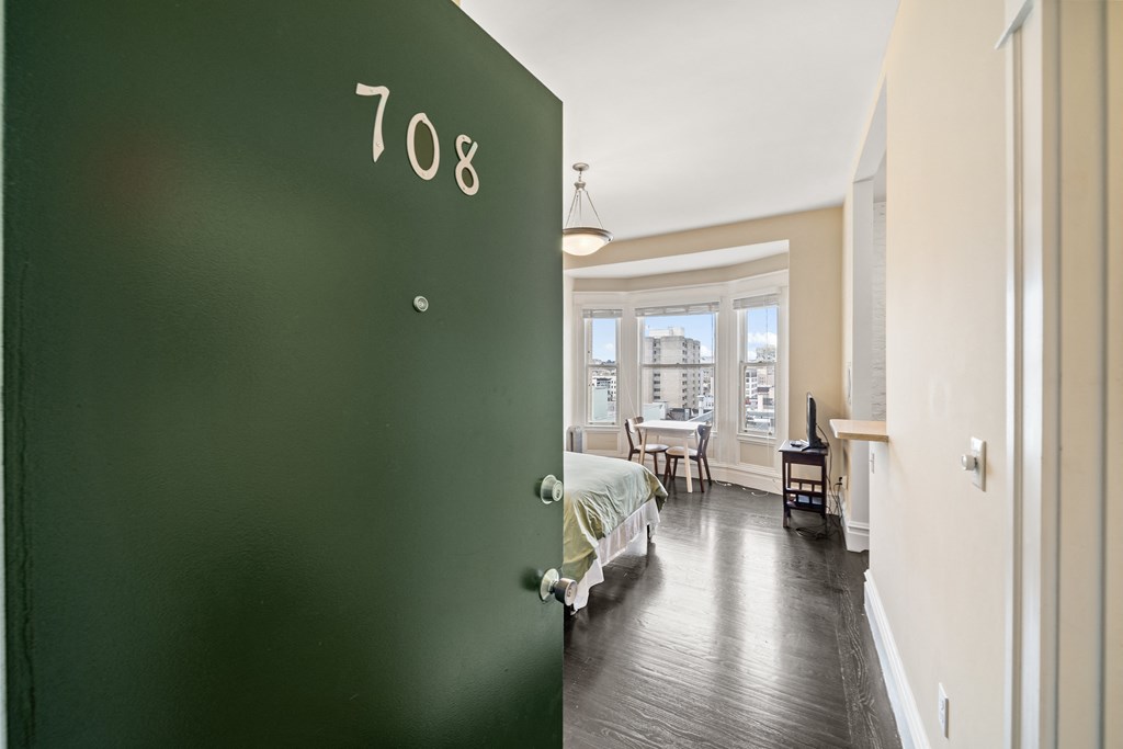 a green door leading into a bedroom with a bed and a window