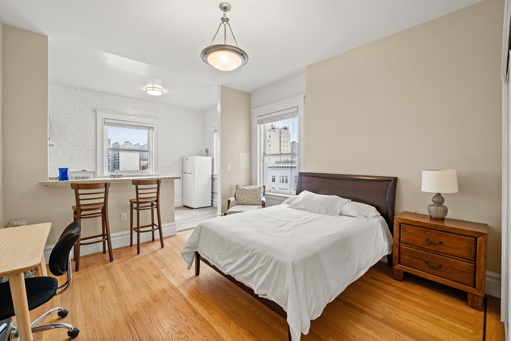 a bedroom with a bed and a kitchen with a desk and chairs