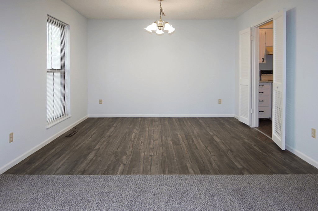A room with wooden flooring and a chandelier hanging from the ceiling.