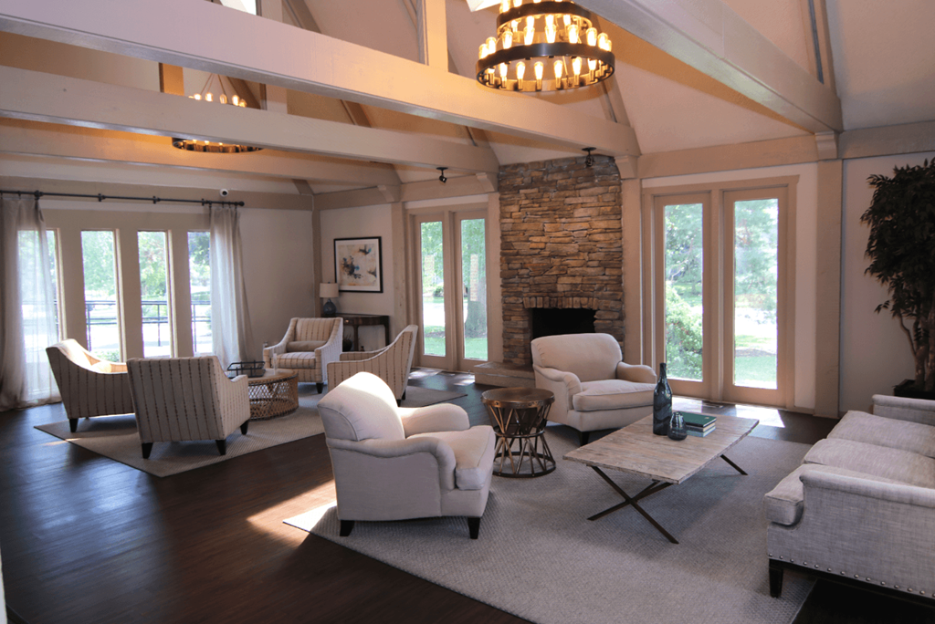 A living room with a stone fireplace and a chandelier.