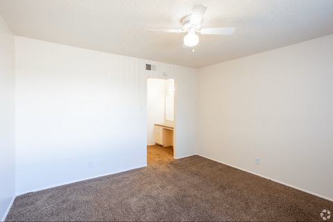 A room with a carpeted floor and a ceiling fan.