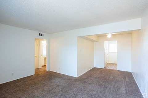 A large, empty room with carpeted flooring and white walls.