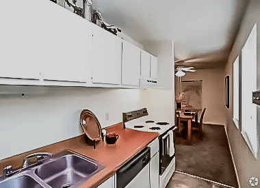 a kitchen and living room with a dining room in the background at Gatehouse Apartments, Kansas City, Missouri