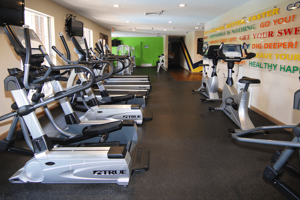A gym with a row of exercise bikes and a green door in the background.