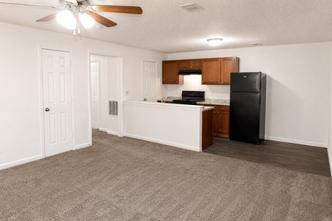 A kitchen with a black refrigerator and white countertops.
