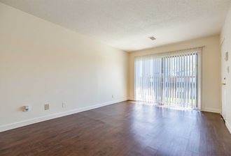 an empty living room with a sliding glass door and wood floors